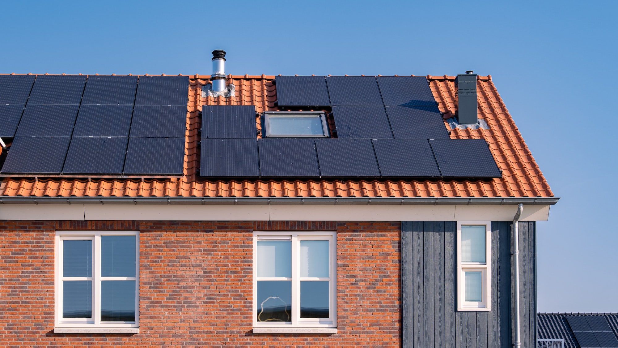 Newly build houses with solar panels attached on the roof against a sunny sky